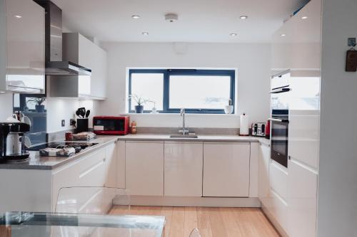 a white kitchen with a sink and a window at Seek Hythe in Hythe