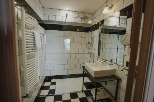 a bathroom with a sink and black and white tiles at Hotel Mercure Roscoff Bord De Mer in Roscoff