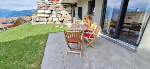 a patio with a table and chairs on a balcony at Le Petit Lu in Leysin