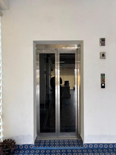a glass elevator in an office building with blue tiles at Cullinan Hotel & Restaurant in Bilāspur