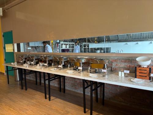 a long counter in a kitchen with chefs in the background at Cullinan Hotel & Restaurant in Bilāspur