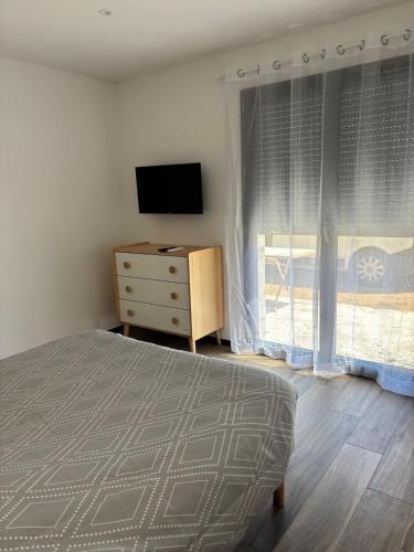 a bedroom with a bed and a dresser with a television at Rez de villa Grand T2 in Sarrola-Carcopino