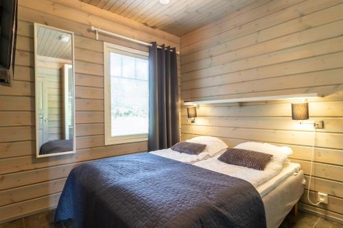a bedroom with a bed in a room with wooden walls at Villa Peso 1&2 - 21 hlö, Both sides, HimosYkkösen alue in Jämsä