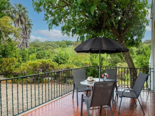 a table and chairs with an umbrella on a balcony at Farmhouse Dreams Explore and Relax in Montemor-o-Novo