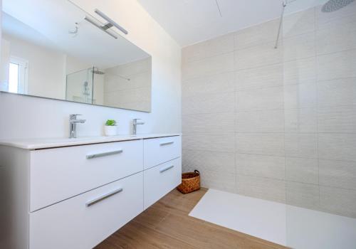 a white bathroom with a sink and a mirror at Serena del Mar by LIVVO in Playa Blanca