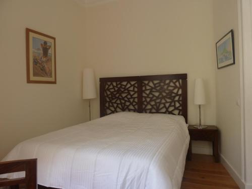 リスボンにあるCasa do Becoの白いベッド1台(木製ヘッドボード付)が備わるベッドルーム1室が備わります。