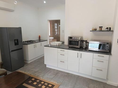 a kitchen with white cabinets and stainless steel appliances at Somerset West Stay 2 in Somerset West