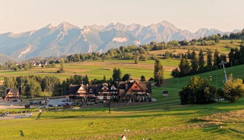 a resort on a hill with mountains in the background at Hotel ZAWRAT Ski Resort & Spa in Białka Tatrzanska