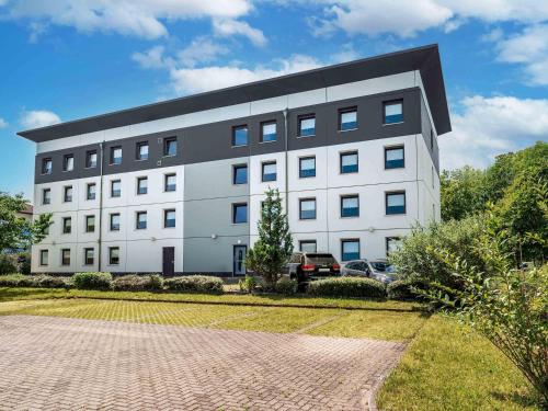 a large white building with a black roof at B&B HOTEL Freiburg-West in Freiburg im Breisgau