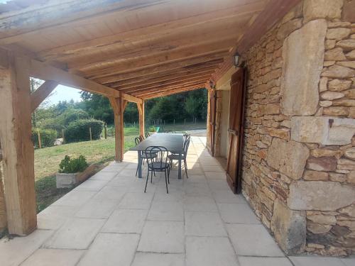 a patio with a table and chairs and a stone wall at Blanquefort Nature Stay in Saint-Cernin-de-lʼHerm