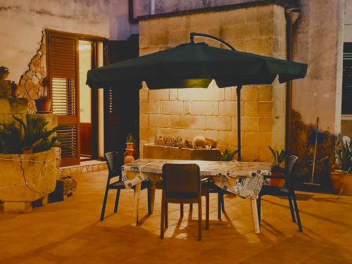 a table with chairs and an umbrella in a room at La casa nel borgo in Acaya