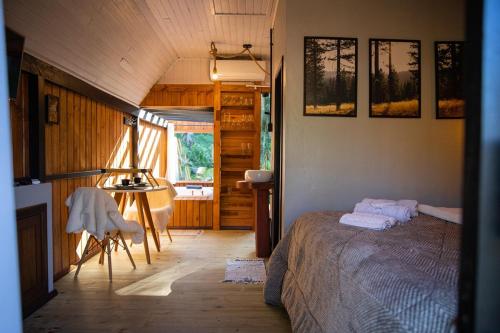 ein Schlafzimmer mit einem Bett und einem Tisch in einem Zimmer in der Unterkunft Cabana Haere Tonu- Seu Refúgio no Coração do Vale Europeu in Benedito Novo