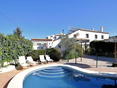 a swimming pool with chairs and a house at Cottage in Villanueva near El Torcal in Villanueva de la Concepción