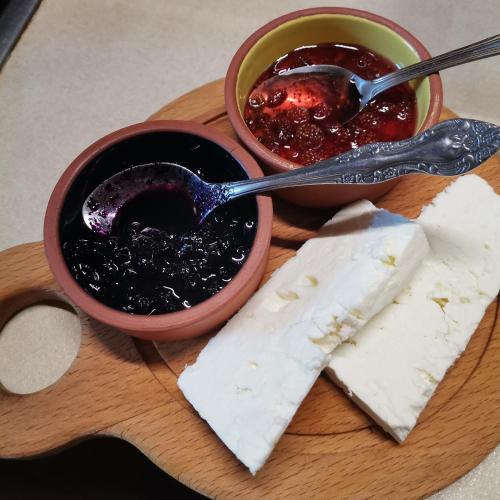 Una tabla de cortar con un tazón de mermelada y algo de comida. en Къщата на музиканта, en Leshten