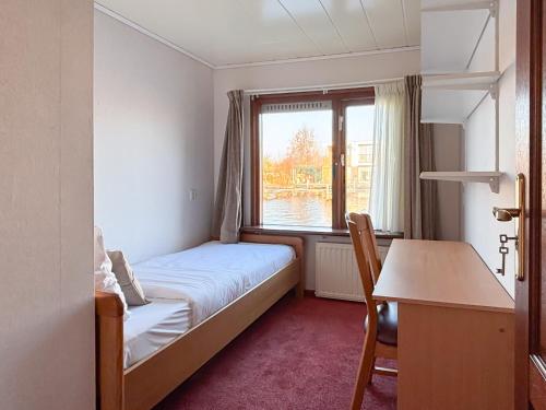 a bedroom with a bed and a desk and a window at VISSERSLUST Rooms, Apartments and Houseboats in Vinkeveen