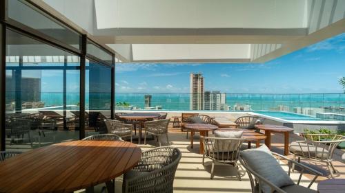 einen Balkon mit Tischen, Stühlen und einem Pool in der Unterkunft Vento Terral - 42m, Novo, Alto Padrão, Frente Mar in Fortaleza