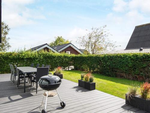 a grill on a deck with a table and chairs at Luxury Beach House with Spa - By Traum Ferienwohnungen in Børkop