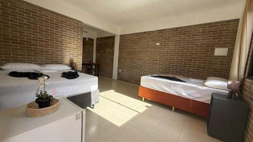 a bedroom with two beds and a brick wall at pousada calango in Aracati