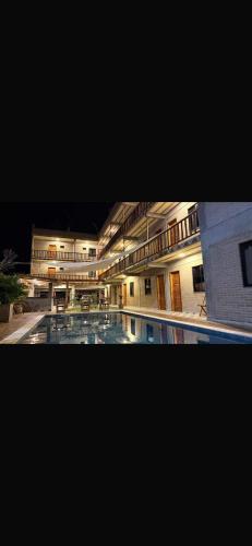 a large building with a swimming pool at night at pousada calango in Aracati