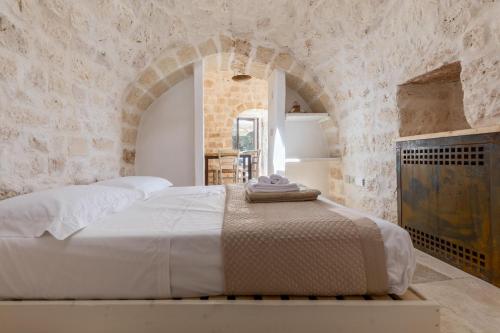 a bedroom with a bed in a stone wall at Tenuta Manfredi by Perle di Puglia in Latiano
