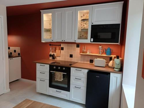 a kitchen with white cabinets and a stove top oven at Petite maison cosy à Moret-sur-Loing, cour privée in Moret-sur-Loing