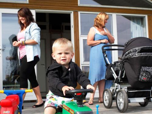 a little boy sitting on a toy stroller with two women at 6 person holiday home in Skærbæk-By Traum in Skærbæk