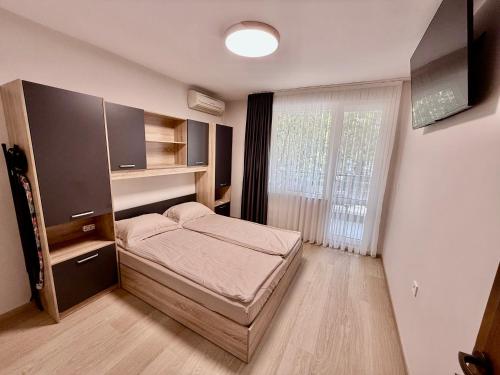 Habitación pequeña con cama y ventana grande. en Beach Please Apartment, en Burgas