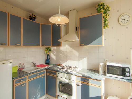 eine Küche mit blauen Schränken, einer Spüle und einer Mikrowelle in der Unterkunft Cozy Garden Retreat Malemort in Malemort-sur-Corrèze