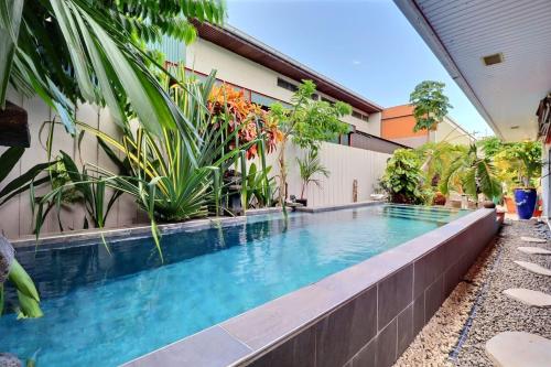 a swimming pool in front of a building with plants at Fare Nãhina - 2 Bedrooms - City Center - Swimming Pool in Papeete