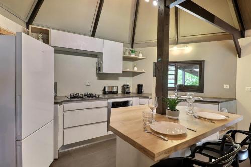 a kitchen with white cabinets and a wooden table at Fare Vainina beach house in Moorea