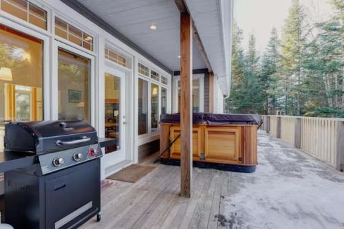 a porch with a grill and a hot tub at Spa and Lakeside - La Luz del Dia in Saint-Didace