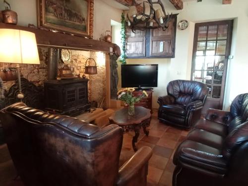 ein Wohnzimmer mit Ledermöbeln und Kamin in der Unterkunft Tranquil Garden Hideaway in Puy-lʼÉvêque