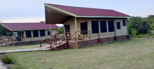 a house with blue windows and a grass field at Oltukai Maasai Mara in Masai Mara
