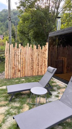 a patio with two chairs and a table and a fence at Pensiunea Atra Doftana in Teşila