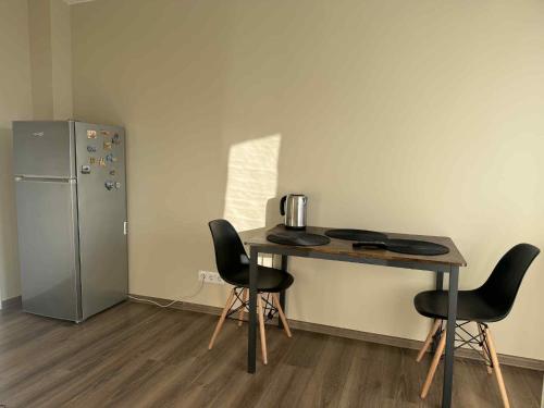 Cette chambre comprend une table avec des chaises et un réfrigérateur. dans l'établissement Apartments Mėguvos, à Palanga