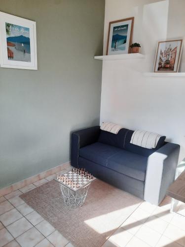 a living room with a blue couch and a table at Maisonnette au bord du Sierroz in Aix-les-Bains