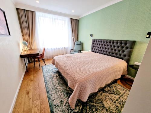 a bedroom with a bed and a desk and a window at Central Stay Appartments in Šiauliai