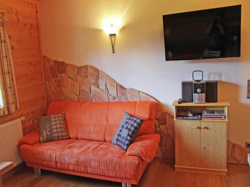 an orange couch in a living room with a tv at Chalet in Sankt Gallenkirch near Ski Bus in Sankt Gallenkirch
