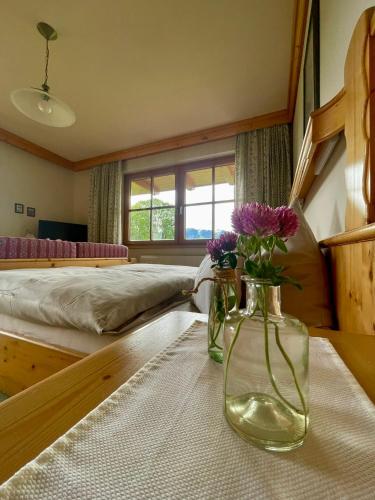 a bedroom with a bed and two vases with flowers on a table at Pension Möslehnerhof in Ramsau am Dachstein