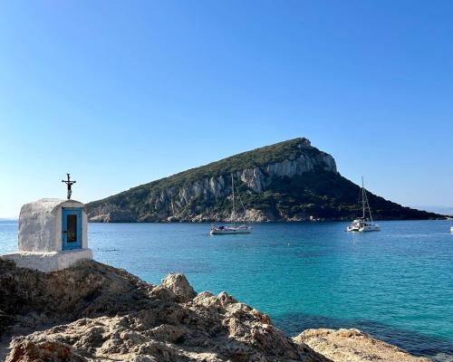 a church on the shore of a body of water with boats at Hotel dP Olbia - Sardinia in Olbia