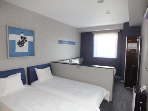 a room with two beds and a window at Henn na Hotel Fukuoka Hakata in Fukuoka