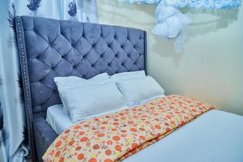 a bedroom with a bed with a blue headboard at Mella home Arusha in Marombosa