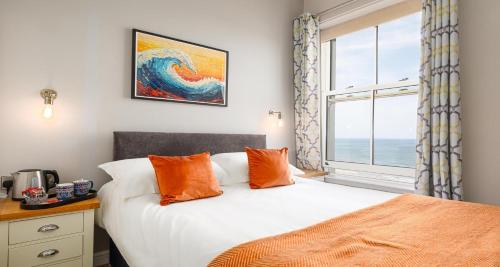 a bedroom with a bed with orange pillows and a window at The Clarence Gardens Hotel, BW Signature Collection in Scarborough