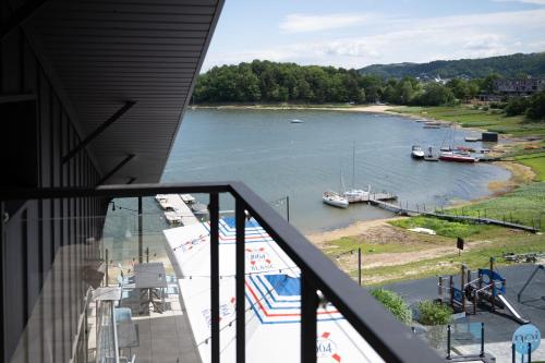 a balcony with a view of a river with boats in it at NOI Resort SPA - woda i las in Tęgoborze