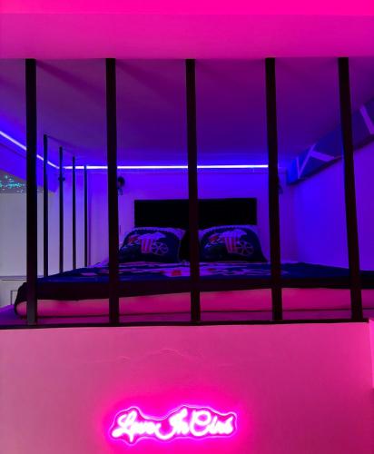 a bed in a room with pink and purple lights at LOVE IN CINÉ Appartement cinéma balnéo in Pamiers
