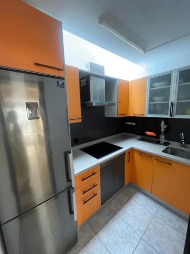cocina con armarios naranjas y nevera de acero inoxidable en La Casita del Tío Juan, en Morro del Jable