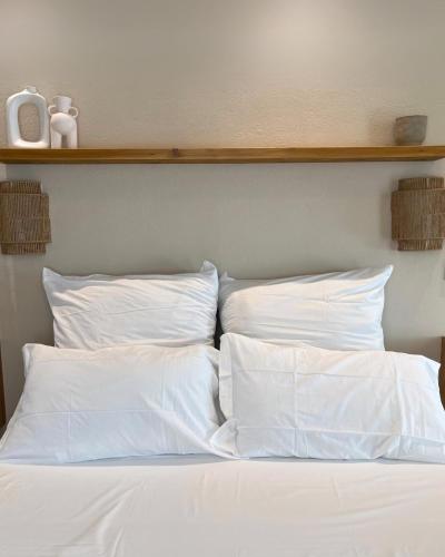 a bed with white sheets and pillows on it at Calèma Apartments in Villasimius