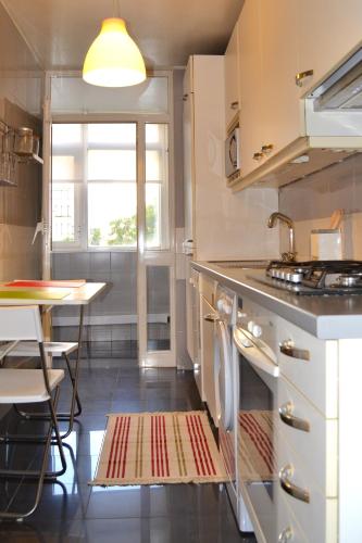 a kitchen with a stove and a table and a window at All in One City Flat - Pool, parking & nomad in Lisbon