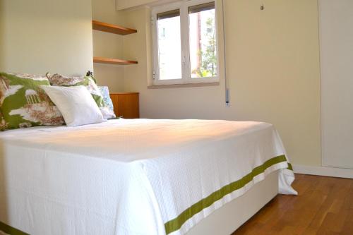 Un dormitorio con una gran cama blanca con ventana. en All in One City Flat - Pool, parking & nomad, en Lisboa