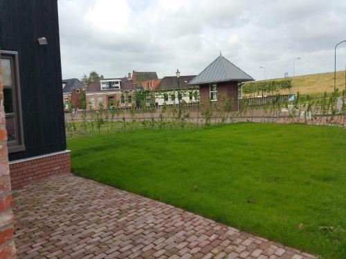 a green yard with a house and a fence at Holiday Home Zoutkamp near Lauwersmeer in Zoutkamp